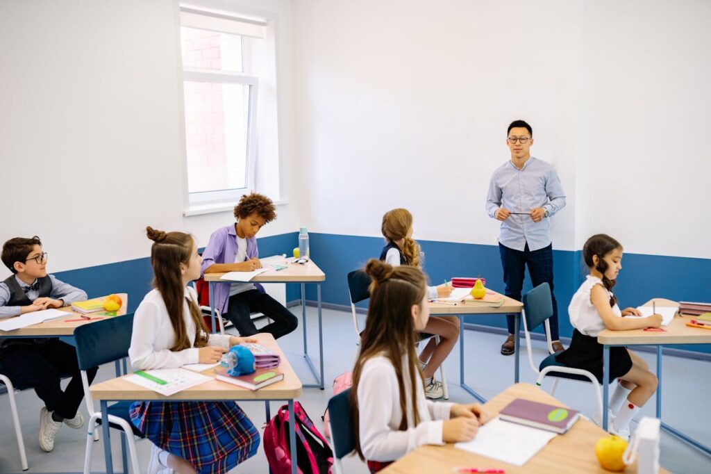 Crafting Captivating Headlines: Your awesome post title goes here Teacher instructing a diverse group of elementary students in a modern classroom setting.
