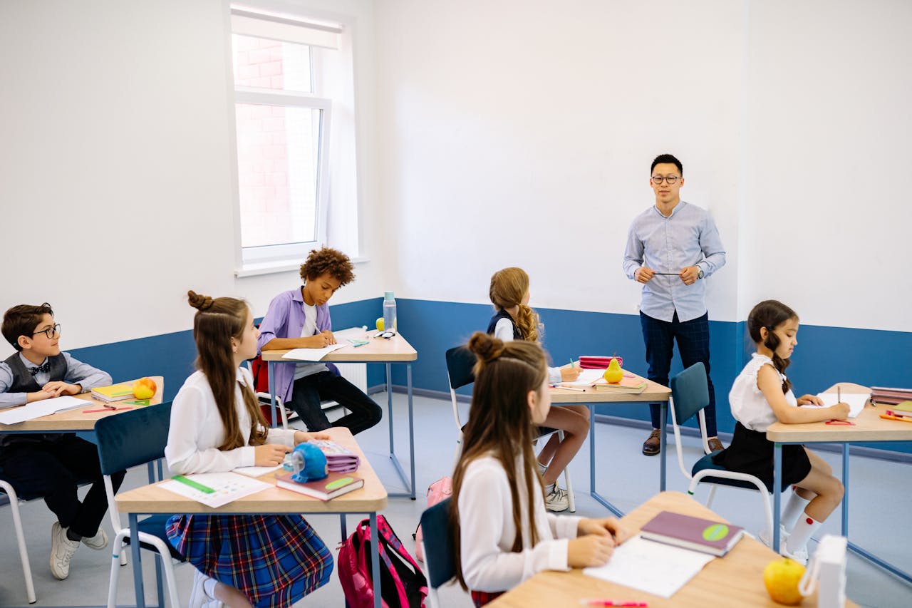 Crafting Captivating Headlines: Your awesome post title goes here Teacher instructing a diverse group of elementary students in a modern classroom setting.